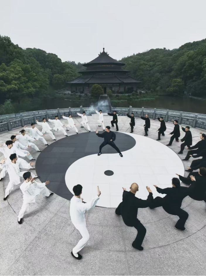 A group practising Tai Chi on a giant yin-yang platform before a temple